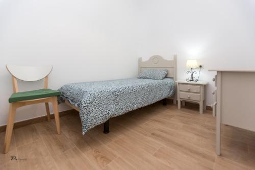 niewielka sypialnia z łóżkiem i krzesłem w obiekcie Fumiko w mieście Sanlúcar de Barrameda
