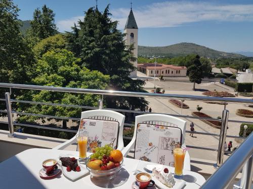 una mesa con un bol de fruta en el balcón en Gloria Apartments 2, en Međugorje