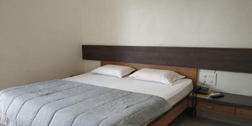 a bedroom with a large bed with a wooden headboard at Hotel Mahendra in Jālgaon
