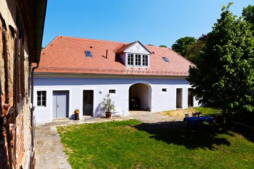ein weißes Haus mit einem roten Dach und einem Hof in der Unterkunft Weingut Haus Steinbach in Radebeul