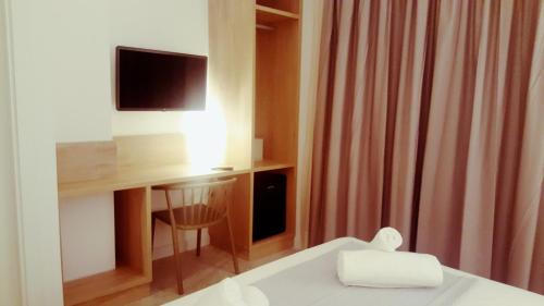 a hotel room with a bed and a desk with a television at Hotel Victori in Es Castell
