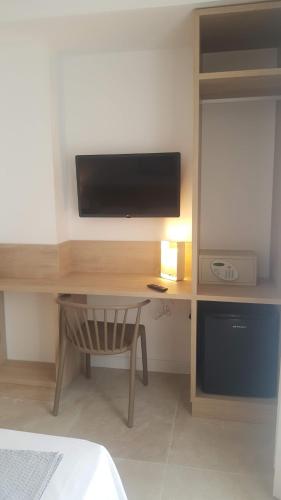 a room with a desk with a television and a chair at Hotel Victori in Es Castell
