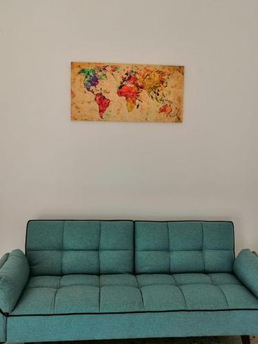 a green couch in a living room with a painting on the wall at Zibibbo Apartment in Pantelleria