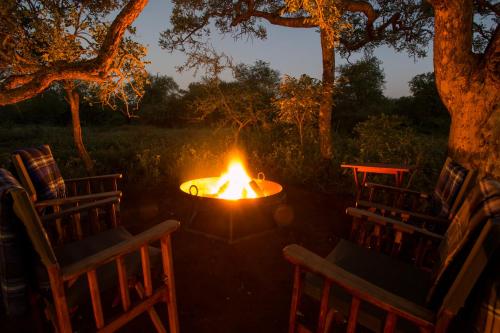 a fire pit with two chairs and a table at Moya Safari Villa in Hoedspruit