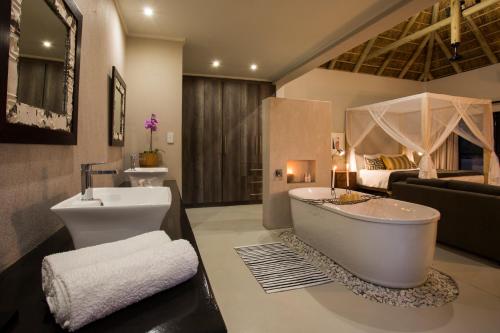 a bathroom with a tub and a sink and a couch at Moya Safari Villa in Hoedspruit