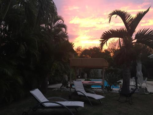 a group of chairs and a gazebo with a sunset at la maison du bonheur in Saint-Pierre