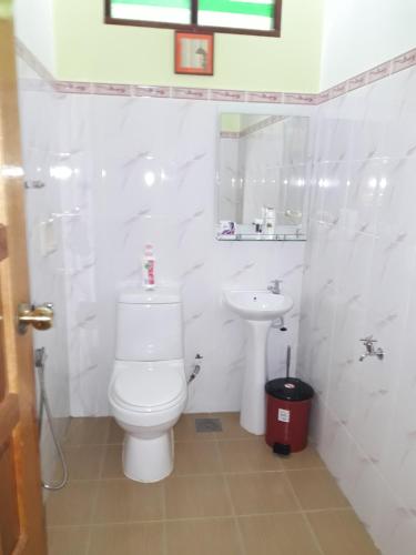 a white bathroom with a toilet and a sink at Anjung Nor Muslim Homestay in Dungun
