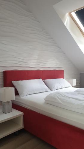 łóżko z czerwonym zagłówkiem w pokoju w obiekcie House-Cora w mieście Stare Miasto