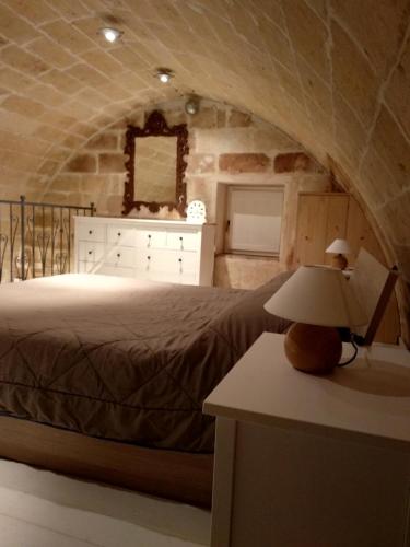 a bedroom with a bed and a table with a lamp at Casa Masiello La casa tipica dei Sassi di Matera in Matera