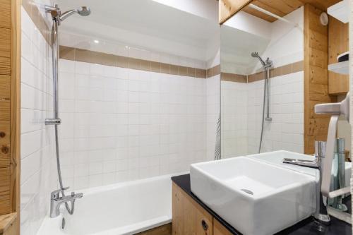 a bathroom with a white sink and a tub at Residence Les Melezes - maeva Home in L'Alpe-d'Huez