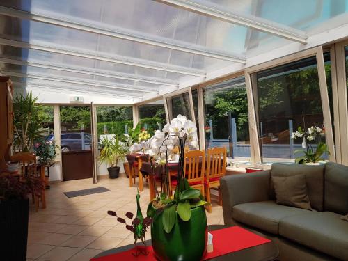 a living room with a conservatory with a table with flowers at B&B Woodside in Torhout