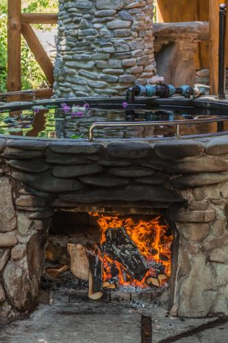 a stone fireplace with a fire in it at Садиба над потоком in Lumshory