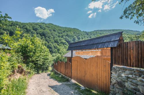 a wooden fence with a stone wall and a building at Садиба над потоком in Lumshory