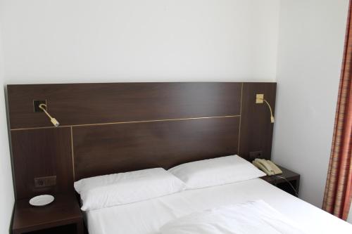 a bed with a wooden headboard with two white pillows at Hotel Montree in Munich