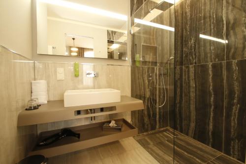a bathroom with a sink and a mirror and a shower at Amelie No 1 Hotel & Appartements in Landau in der Pfalz