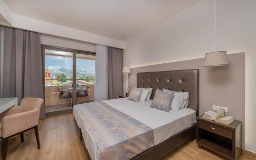 Schlafzimmer mit einem Bett, einem Schreibtisch und einem Fenster in der Unterkunft Oscar Hotel in Laganas