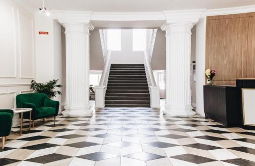 a lobby with white columns and a staircase at Готель Континент Миколаїв in Mykolaiv