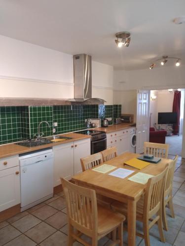 uma cozinha com uma mesa de madeira com cadeiras e um lavatório em Castle Square Apartments Beaumaris em Beaumaris
