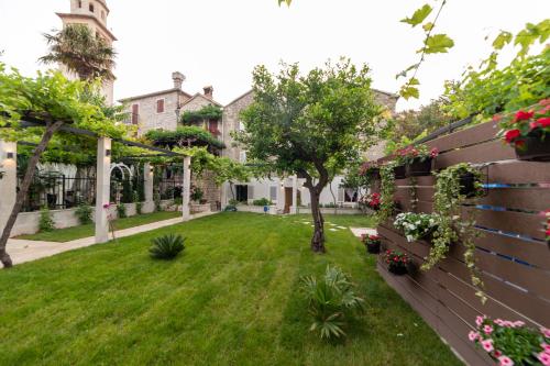 a yard of a house with a fence and flowers at Apartments Trifunovic Old Town in Budva