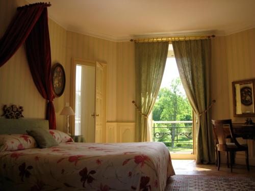 een slaapkamer met een bed en een groot raam bij Château de Vaulogé in Fercé-sur-Sarthe