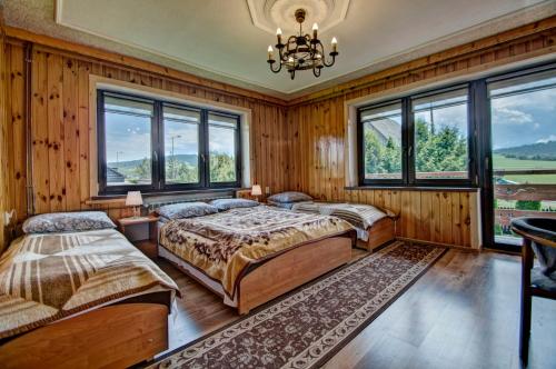 a bedroom with two beds and windows and a chandelier at Dom Na Borku in Ciche