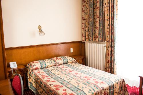 a bedroom with a bed with a floral bedspread at Hotel Continental Gare du Midi in Brussels