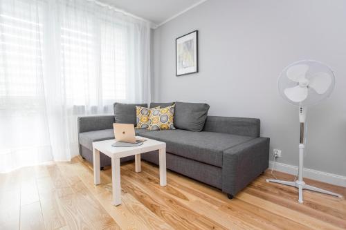 Una sala de estar con un sofá y una mesa con una computadora portátil. en CR Wygodny Apartament w Centrum Nowy Świat 13, en Białystok
