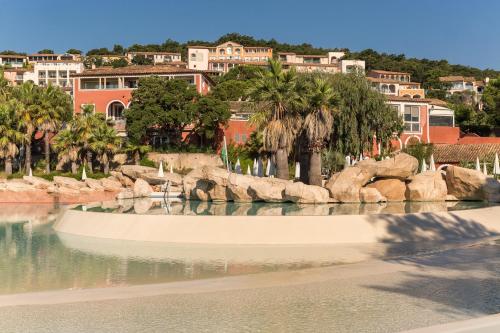 グリモーにあるRésidence Pierre & Vacances Les Restanques du Golfe de Saint-Tropezの木々や建物を背景にした水のプール