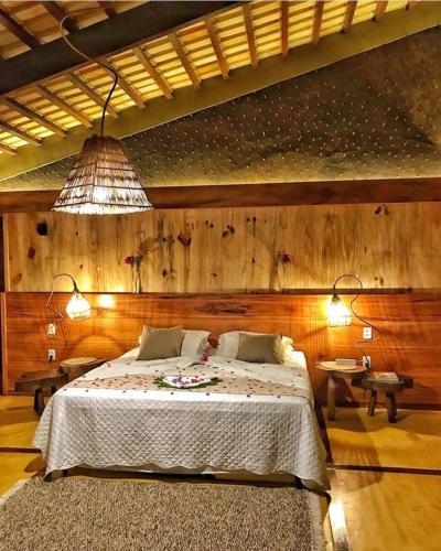 a bedroom with a large bed and a chandelier at Canoé Brasil in Praia de Moitas