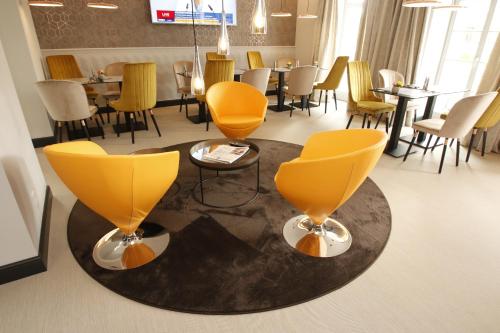 a restaurant with yellow chairs and tables and chairs at Amelie No 1 Hotel & Appartements in Landau in der Pfalz
