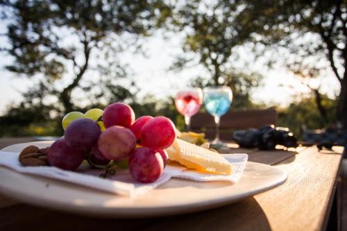 a plate of grapes and cheese on a table with wine glasses at Moya Safari Villa in Hoedspruit