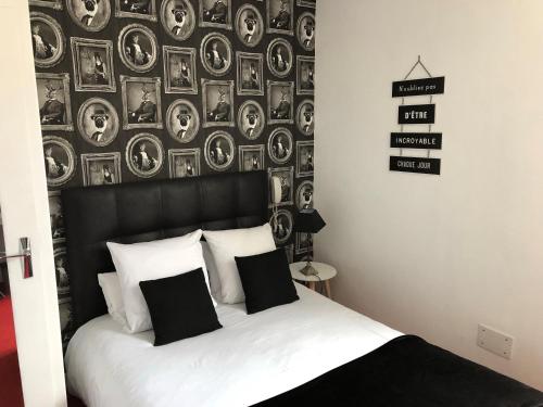 a bedroom with a bed with a wall with pictures at Hotel Reine Mathilde in Bayeux