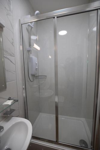 a shower with a glass door next to a sink at PremierLux Serviced Apartments in Ilford