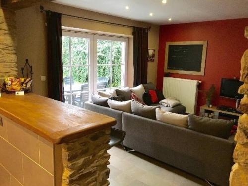 a living room with couches and a kitchen with a table at Gîte "L'échappée amoureuse et féérique" in Paliseul