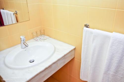 a white sink sitting under a white towel at Hotel Aros in Tychy