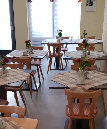 una habitación con mesas y sillas con flores. en Pension zum Hecht en Schemmerberg