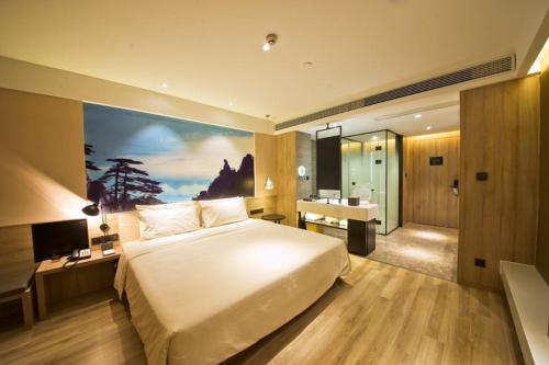 a bedroom with a large bed and a desk and a sink at Atour Hotel Phoenix Avenue Shangrao in Shangrao