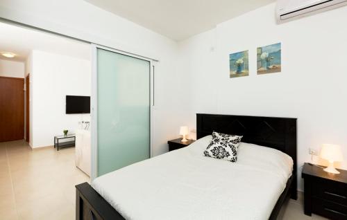 - une chambre avec un lit blanc et un mur en verre dans l'établissement Home4Trip Bat Yam, à Bat Yam