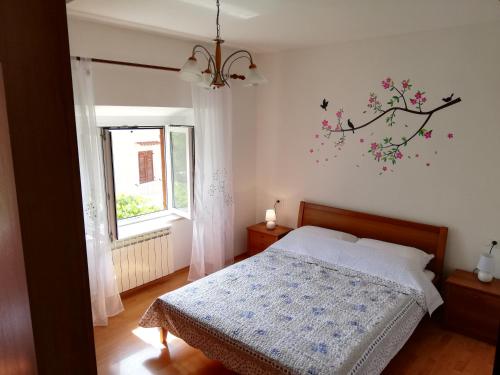 a bedroom with a bed and a tree mural on the wall at Apartment Luka in Mali Lošinj