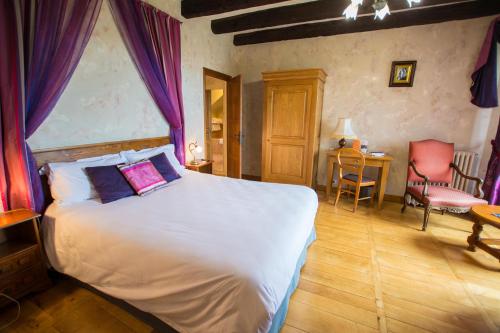 a bedroom with a large bed with purple curtains at La Terrasse - Teritoria in Meyronne