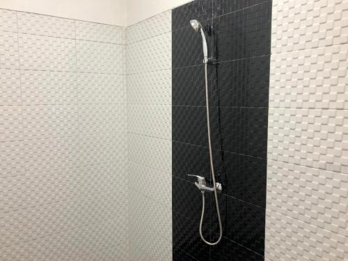 a shower with black and white tiles in a bathroom at Nata Homestay in Nusa Lembongan