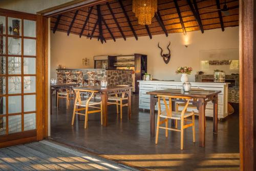 a kitchen and dining room with tables and chairs at Mbizi Bush Lodge in Grietjie Nature Reserve