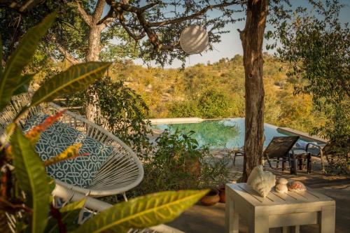 a patio with a table and chairs and a pool at Mbizi Bush Lodge in Grietjie Nature Reserve