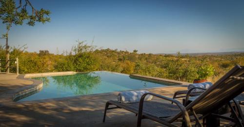 a swimming pool with two chairs next to at Mbizi Bush Lodge in Grietjie Nature Reserve