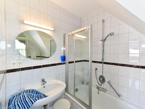 ein weißes Bad mit einem Waschbecken und einer Dusche in der Unterkunft Ferienwohnungen Meyer in Hochbuch