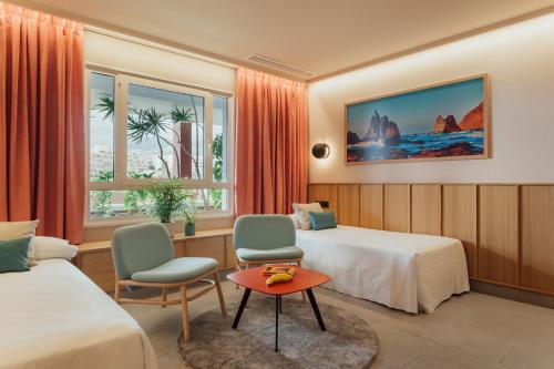 Cette chambre d'hôtel comprend deux lits, une table et des chaises. dans l'établissement Adrián Hoteles Roca Nivaria, à Adeje