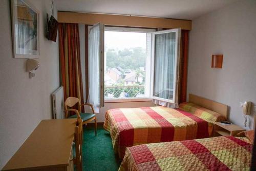 a hotel room with two beds and a window at Hôtel Sainte Suzanne in Lourdes