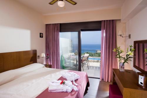 a hotel room with a bed and a view of the ocean at Elounda Olea Villas And Apartments in Elounda