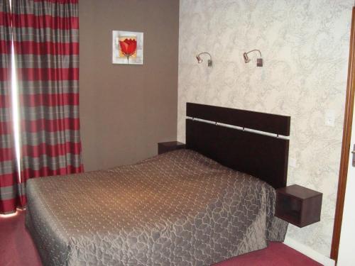 a bedroom with a bed and two lights on the wall at Hôtel de La Croix d'Or in Avranches