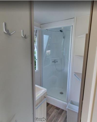 une salle de bain blanche avec une douche et un lavabo dans l'établissement Camping LE PIGEONNIER, à Saint-Crépin-et-Carlucet